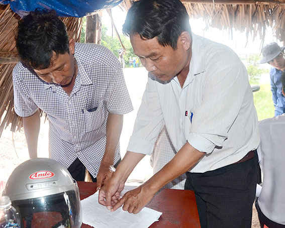 Anh Nguyễn Công Biên, đại diện các hộ nuôi cá lồng bè trên sông Chà Và (bìa trái) trao đổi về lịch điều tiết xả nước cống số 6 với ông Nguyễn Huỳnh Châu, nhân viên Trạm quản lý khai thác công trình thủy lợi huyện Tân Thành.