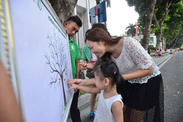 Những bạn trẻ thích thú vẽ màu lá xanh trên bức tranh cam kết bảo vệ môi trường.