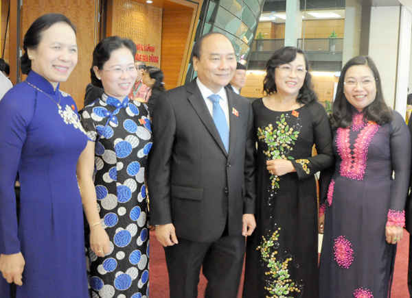 Trước giờ khai mạc, bên hành lang Quốc hội sáng 20/10, Thủ tướng Nguyễn Xuân Phúc chúc mừng các đại biểu nữ nhân ngày truyền thống Phụ nữ Việt Nam. Ảnh: Việt Hùng