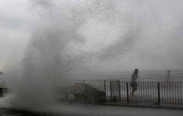 Mọi người chạy thoát khỏi làn sóng lớn trên một bờ sông khi bão Haima đổ bộ vào Hong Kong, Trung Quốc vào ngày 21/10/2016. Ảnh: REUTERS / Bobby Yip
