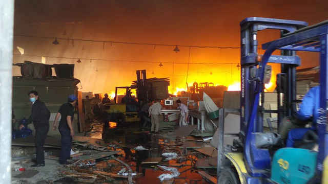 Phía trong cháy lớn, phía ngoài các công nhân vẫn đang nỗ lực giải cứu hàng hóa.