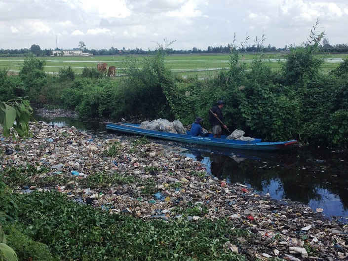 Công nhân của đơn vị quản lý bãi rác thải xã Đông Thắng đang thu gom rác trên kênh Bờ Thiếc.