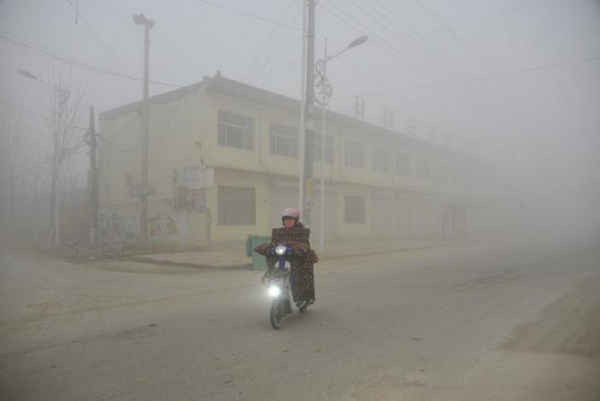 Người dân đi xe trên đường trong bầu không khí dày đặc sương mù tại Liêu Thành, tỉnh Sơn Đông vào ngày 20/12/2016. Ảnh: REUTERS / Stringer