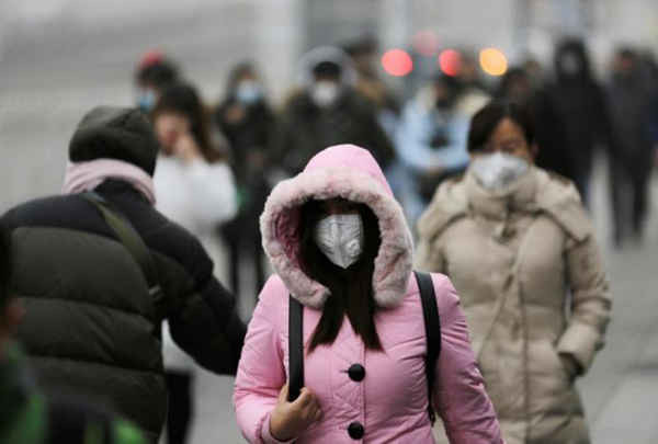 Người dân đeo khẩu trang đến nơi làm việc trong sương mù sau khi báo động đỏ được ban hành ở trung tâm thương mại của Bắc Kinh, Trung Quốc vào ngày 21/12/2016. Ảnh: REUTERS / Jason Lee