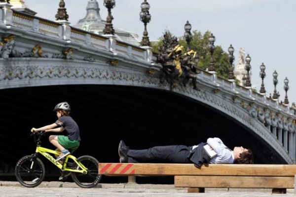 Người đàn ông nằm dưới ánh mặt trời, gần cầu Alexandre III dọc theo sông Seine ở Paris vào ngày 26/8/2013. Ảnh: REUTERS / Charles Platiau