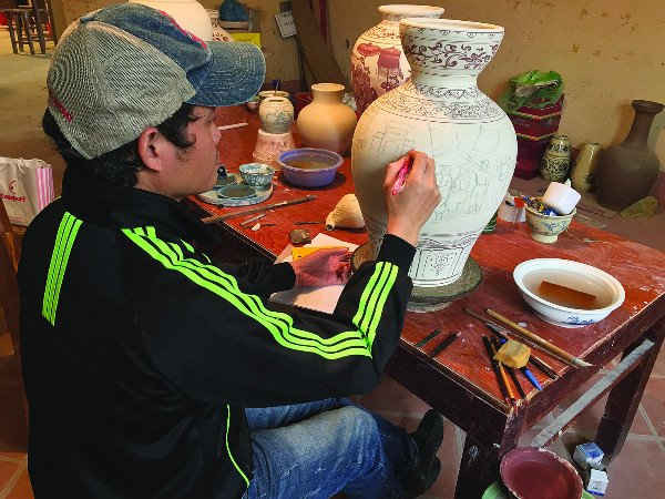 Nghệ nhân gốm Chu Đậu Hạ Bá Định thực hiện những nét vẽ phỏng lại xã hội Việt thời xưa