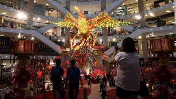 Du khách đi qua mô hình gà trống khổng lồ được cài đặt tại trung tâm mua sắm ở Kuala Lumpur, Malaysia.