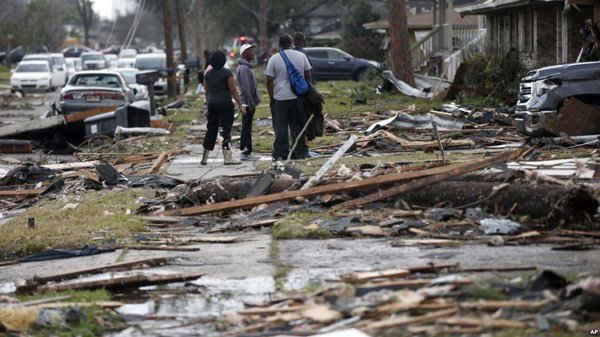 Mọi người đi bộ giữa các mảnh vỡ từ ngôi nhà bị phá hủy sau khi cơn lốc xoáy xé qua khu vực lân cận phía Đông ở New Orleans vào ngày 7/2/2017