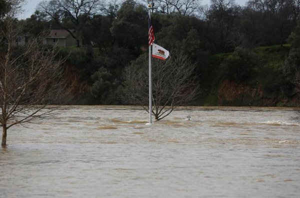 Lá cờ California bay trong khu Riverbend Park bị ngập lụt do nước xả ra từ đập Oroville sau khi lệnh sơ tán được ban bố tại các khu dân cư ở hạ lưu đập Oroville, tại Oroville, California, Mỹ vào ngày 13/2/2017. Ảnh: REUTERS / Jim Urquhart
