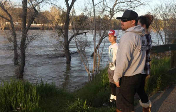 Cư dân Oroville đứng nhìn dòng sông Feather sau khi lệnh sơ tán được dỡ bỏ ở hạ lưu đập Oroville ở bang California, Mỹ vào ngày 14/2/2017. Ảnh: REUTERS / Jim Urquhart