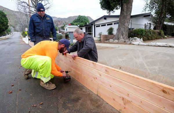 Kỹ sư của Cơ quan Dịch vụ tại chỗ California đang lắp đặt các tấm gỗ để bảo vệ ngôi nhà khỏi lở đất và nước lũ trước dự báo về tình hình thời tiết khắc nghiệt tại bờ biển phía tây. Ảnh: REUTERS / Ringo Chiu
