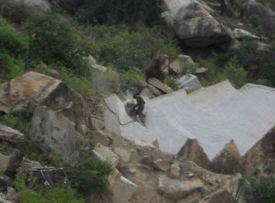 Một “đá tặc” đang dùng khoan máy “xẻ thịt” một tảng đá lớn nằm lưng chừng núi Bà. 