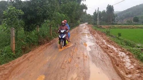 Mặc dù trời không mưa nhưng để ra ngoài với đoạn đường đầy bùn như vậy người dân Liên Trạch phải mặc áo mưa khi đi lại. Ảnh: Phan Phương