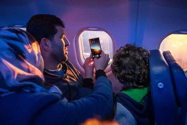 Hành khách nhìn ra cửa sổ của máy bay và chụp ảnh trên chuyến bay qua dãy Alps của Thụy Sĩ. Ảnh: IOM / Muse Mohammed