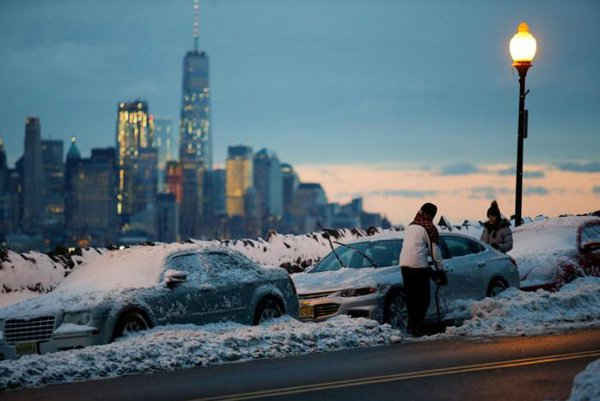 Người dân lau dọn xe và những con đường phủ đầy tuyết ở Weehawken, New Jersey khi Trung tâm Thương mại Một Thế giới và vùng Hạ Manhattan vừa trải qua trận bão tuyết ở New York, Mỹ vào ngày 14/3/2017. Ảnh: REUTERS / Eduardo Munoz