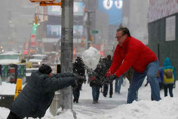 Một người đàn ông và đứa trẻ chơi đánh tuyết ở Quảng trường Thời đại trong một cơn bão tuyết ở New York. Ảnh: REUTERS / Carlo Allegri
