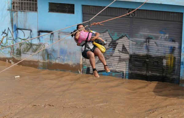 Một phụ nữ và một đứa trẻ được cứu bằng đường dây zip sau khi dòng sông Huayco tràn bờ khiến nước chảy qua các đường phố ở Huachipa, Peru vào ngày 17/3/2017. Ảnh: REUTERS / Guadalupe Pardo
