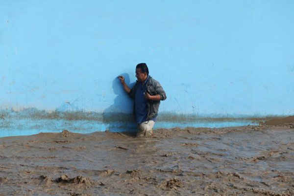 Người đàn ông đi qua một con đường bị ngập nước sau khi dòng sông Huayco tràn bờ khiến nước chảy qua các đường phố ở Huachipa, Peru vào ngày 17/3/2017. Ảnh: REUTERS / Guadalupe Pardo