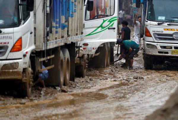 Người dân dọn bùn từ lốp xe tải ở đường cao tốc Trung tâm sau khi lở đất xảy ra ở Huarochiri, Lima, Peru vào ngày 23/3/2017. Ảnh: REUTERS / Guadalupe Pardo
