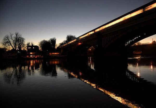 Hình ảnh tàu hỏa chở khách được phản chiếu qua sông Thames vào lúc hoàng hôn ở Richmond, Tây London, Anh vào ngày 1/12/2016. Ảnh: REUTERS / Toby Melville