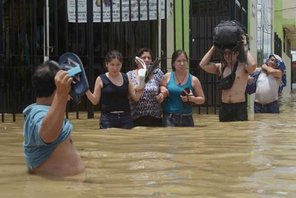 Các cư dân lội qua con đường bị ngập nước sau khi các con sông vỡ bờ do mưa xối xả, gây ngập lụt và phá hủy trên diện rộng ở Piura, Peru vào ngày 27/3/2017. Ảnh: REUTERS / Miguel Arreategui