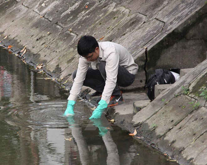 Cán bộ Trung tâm Quan trắc môi trường tỉnh lấy mẫu nước sông xét nghiệm, tìm nguyên nhân cá chết. (Ảnh: Thu Hoài/TTXVN)