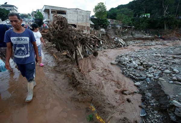 Người dân đi bộ trong khu vực bị phá hủy sau trận mưa lớn khiến một số dòng sông tràn bờ, trầm tích và đá bị cuốn trôi vào các tòa nhà và các con đường tại Mocoa, Colombia vào ngày 1/4/2017. Ảnh: REUTERS / Jaime Saldarriaga