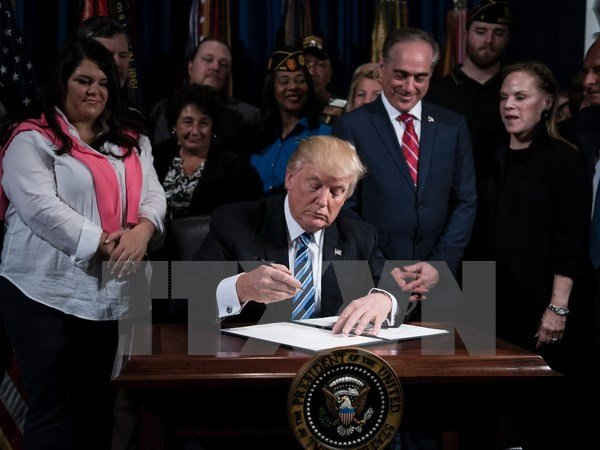 Tổng thống Mỹ Donald Trump (giữa) ký một sắc lệnh ở Washington, DC ngày 27/4. (Nguồn: AFP/TTXVN)