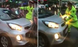 Chiến sĩ CSGT bị chiếc xe taxi lao thẳng vào người buộc phải né tránh. (Ảnh cắt từ clip)