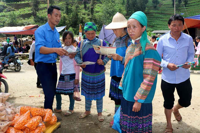 Cán bộ tỉnh đoàn Lào Cai phát tờ rơi và giải thích về tầm quan trọng của nước sạch và VSMT cho bà con hiểu.