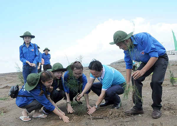 Bộ trưởng Trần Hồng Hà hướng dẫn các bạn trẻ xã Đất Mũi, huyện Ngọc Hiển, tỉnh Cà Mau trồng cây chắn sóng đúng quy cách