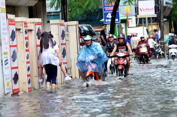 Đôi bạn trẻ cõng nhau băng qua vùng nước ngập