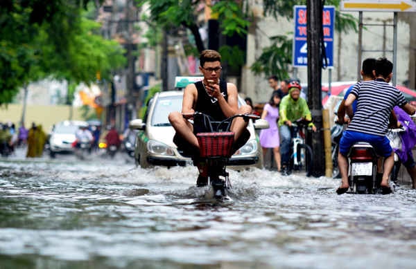 Chàng thanh niên ung dung trên chiếc xe máy điện băng qua dòng nước ngập