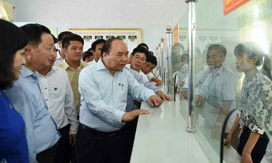 Thủ tướng Nguyễn Xuân Phúc và Đoàn công tác của Chính phủ trò chuyện với cán bộ Bộ phận tiếp nhận và trả kết quả theo cơ chế 1 cửa tại UBND xã Tượng Sơn. 