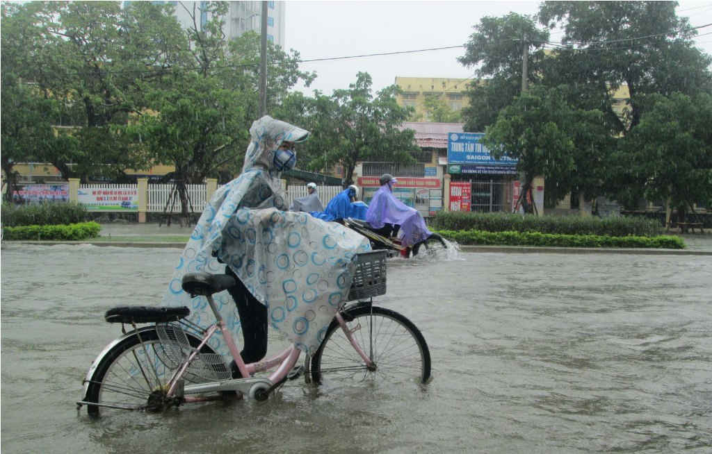 Một em học sinh dắt xe đạp dưới nước