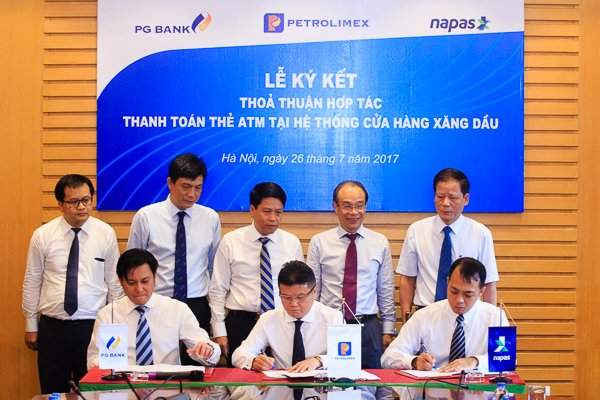 Phó TGĐ Petrolimex Phạm Đức Thắng (ở giữa), PhóTGĐ Napas Nguyễn Đăng Hùng (bên trái), TGĐ PG Bank Nguyễn Quang Định (bên phải) ký kết thỏa thuận