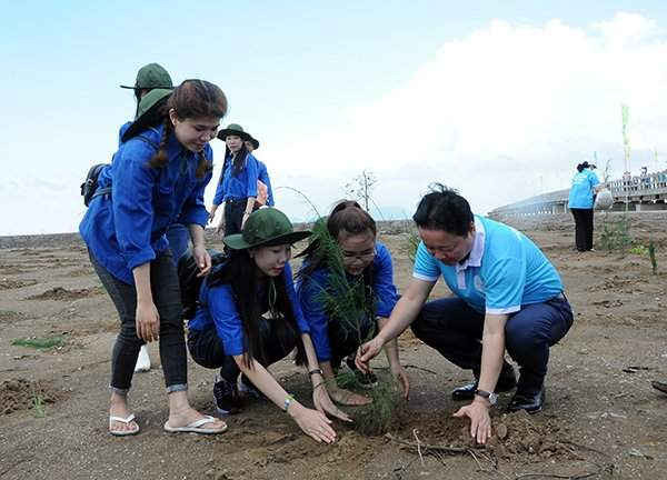 Bộ trưởng Trần Hồng Hà hướng dẫn đoàn viên thanh niên xã Đất Mũi, huyện Ngọc Hiển, tỉnh Cà Mau phương pháp trồng cây chắn sóng