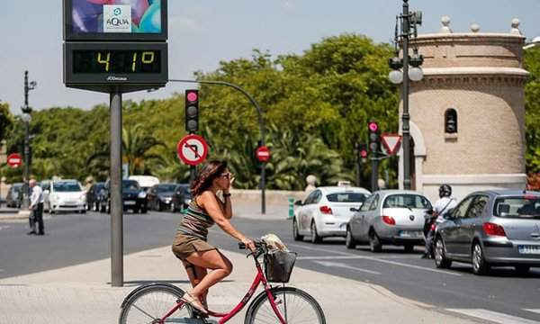 Một người đi xe đạp đang chờ để qua đường bên cạnh nhiệt kế hiển thị 41 độ C ở Valencia, Tây Ban Nha. Ảnh: Manuel Bruque / EPA