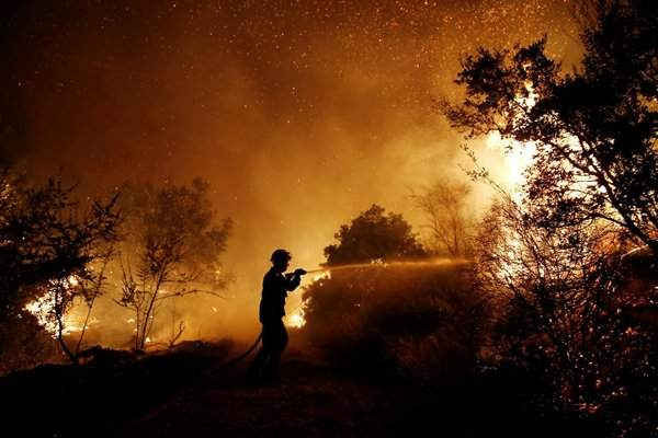 Một lính cứu hỏa nỗ lực dập tắt lửa rừng gần Kalamos. Hình ảnh: Costas Baltas / Reuters