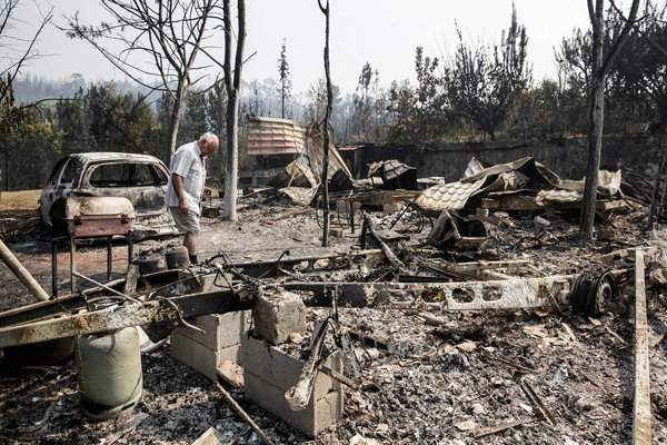 Người đàn ông cúi nhìn những thứ bị tàn phá sau khi cháy rừng lan qua làng Outeiro do Forno, miền Trung Bồ Đào Nha. Ảnh: Paulo Cunha / EPA