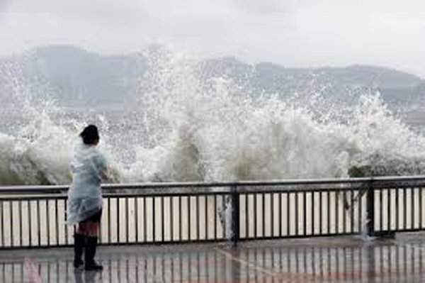Người phụ nữ đứng ngay cạnh làn sóng lớn trên bờ sông khi bão Hato tấn công Hồng Kông, Trung Quốc vào ngày 23/8/2017.