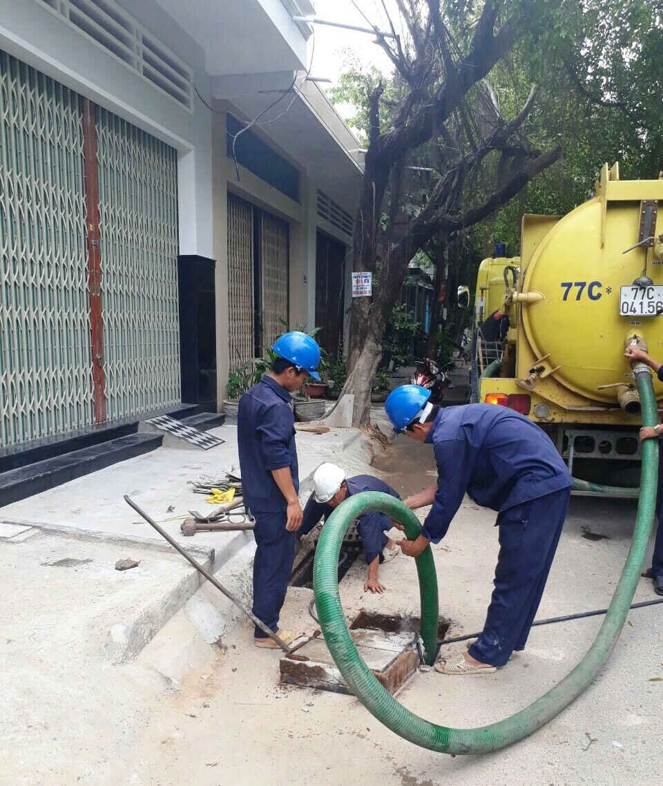 Công nhân Công ty Cổ phần Môi trường Đô thị Quy Nhơn đang nạo vét bùn đất, chất thải dưới các cụm hố ga tại đường Trần Hưng Đạo (TP Quy Nhơn).