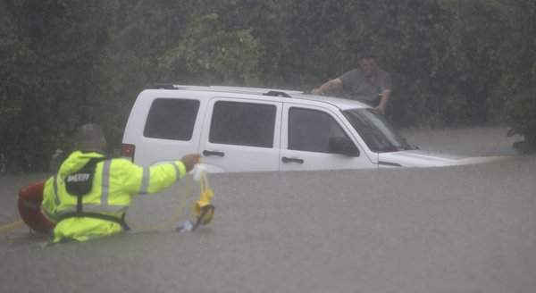 Wilford Martinez (bên phải) chờ đợi cứu hộ sau khi chiếc xe của ông bị mắc kẹt trong lũ. Ảnh: David J. Phillip / AP