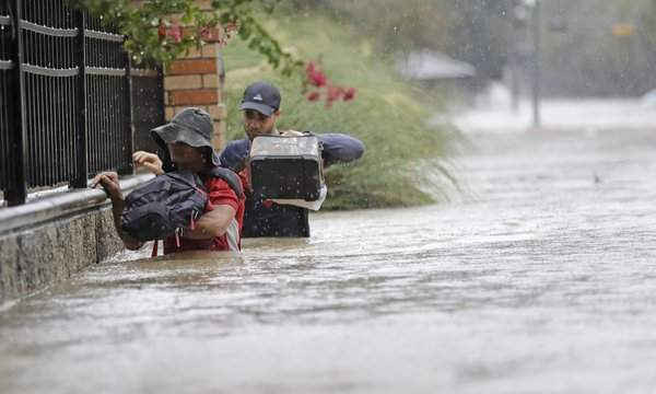 Người dân lội qua dòng nước lũ ở Houston. Ảnh: David J Phillip / AP