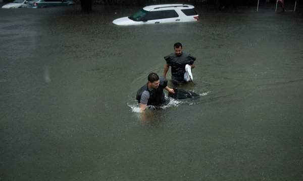 Mọi người lội qua các con phố bị ngập lụt sau bão Harvey. Ảnh: Brendan Smialowski / AFP / Getty Images