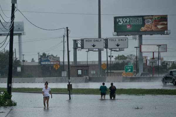 Người dân đi bộ qua các con phố bị ngập lụt sau cơn bão Harvey. Ảnh: Brendan Smialowski / AFP / Getty Images