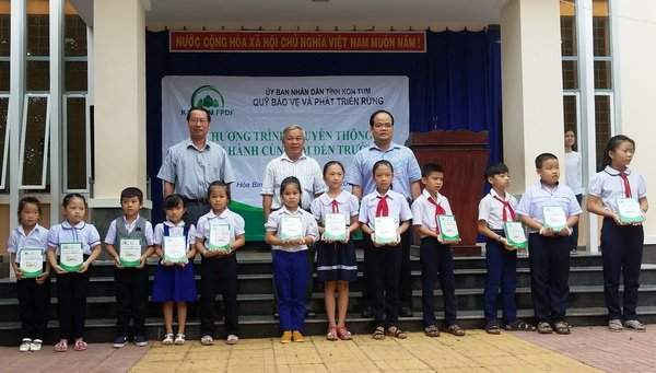 Ông Hồ Thanh Hoàng - Giám đốc Quỹ Bảo vệ và Phát triển rừng Kon Tum cùng đại diện Đảng ủy xã Hòa Bình và Thầy Hiệu trưởng trao vở cho các em học sinh