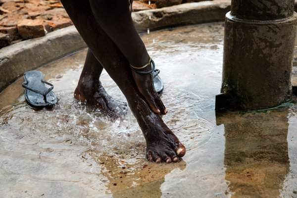 Một phụ nữ rửa mặt bằng nước cấp từ nhà máy xử lý đến máy bơm tại trường tiểu học Machakos vào tháng 7/2017. Những phụ nữ sống quanh đây thường đến máy bơm này hàng ngày để lấy nước uống và nước sinh hoạt an toàn cho gia đình.
