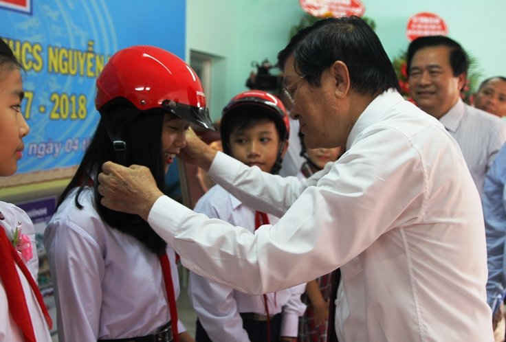 Nguyên Chủ tịch nước Trương Tấn Sang trao mũ bảo hiểm cho các em học sinh trường THCS Nguyễn Văn Chính. 