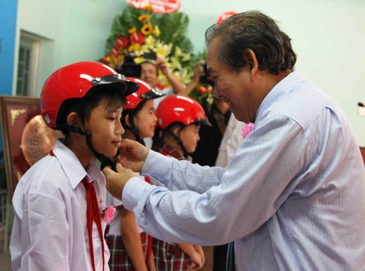 Phó Thủ tướng Thường trực Chính phủ Trương Hòa Bình trao mũ bảo hiểm cho các em học sinh trường THCS Nguyễn Văn Chính.